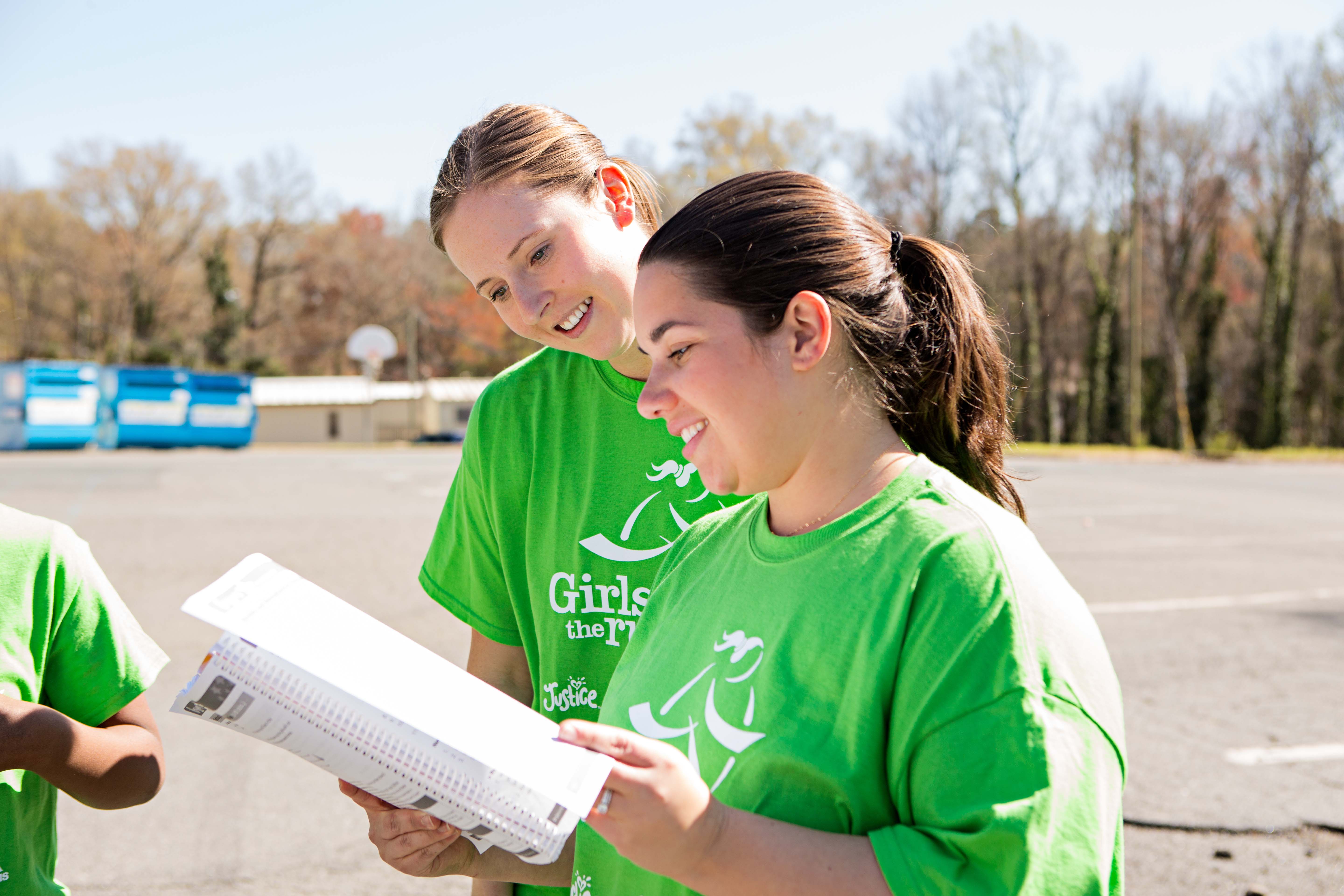 Smiling Girls on the Run Coach holding lesson plan 